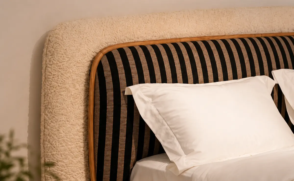 Close-up of a bed headboard in striped velvet with a boucle border and a timber trim