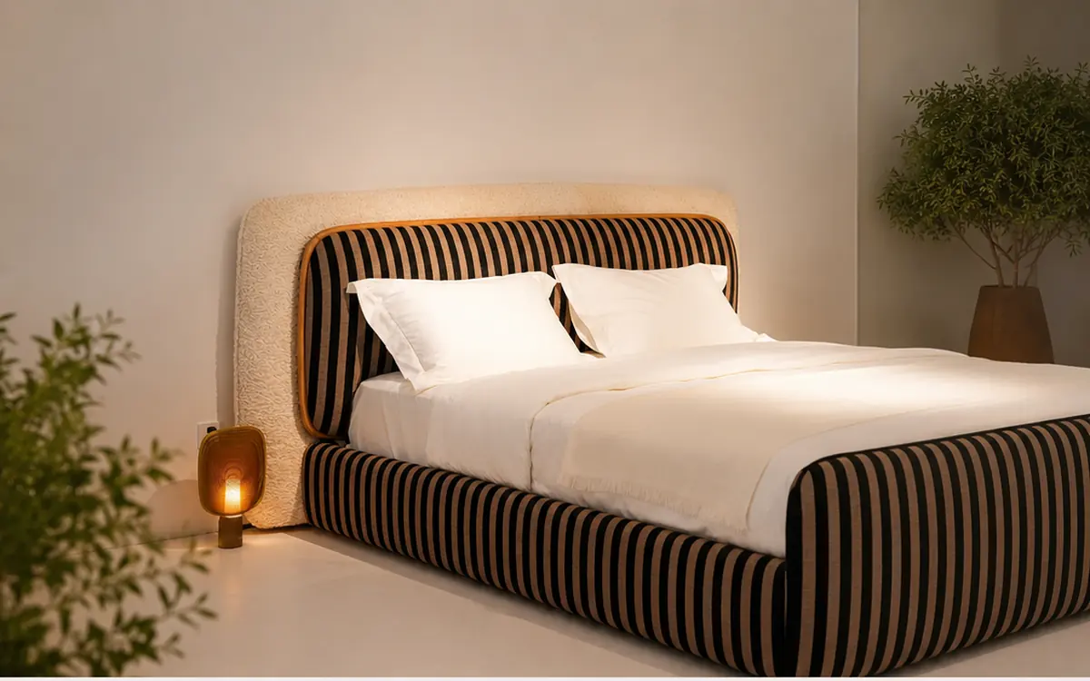 Upholstered bed with a striped velvet headboard framed by a cream boucle panel, in a softly lit bedroom