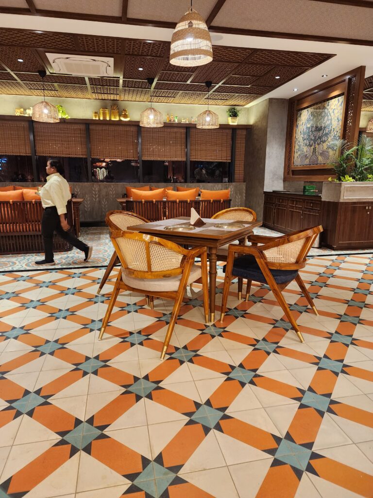 Stylish restaurant furniture by Mavensoft in a Hyderabad dining space, with cane-back chairs and wood table on patterned tile flooring.