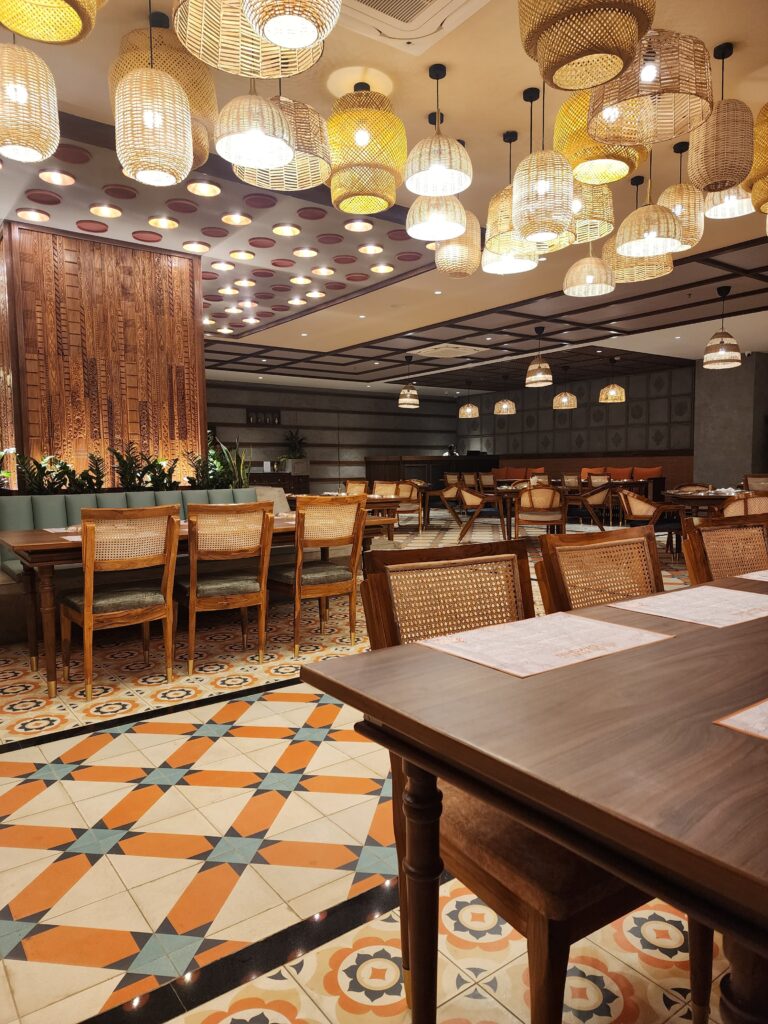 Stylish restaurant furniture by Mavensoft in a Hyderabad dining space, with cane-back chairs and wood table on patterned tile flooring.