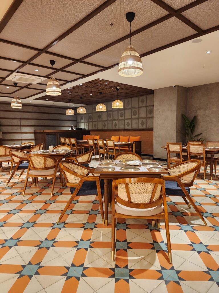 Stylish restaurant furniture by Mavensoft in a Hyderabad dining space, with cane-back chairs and wood table on patterned tile flooring.