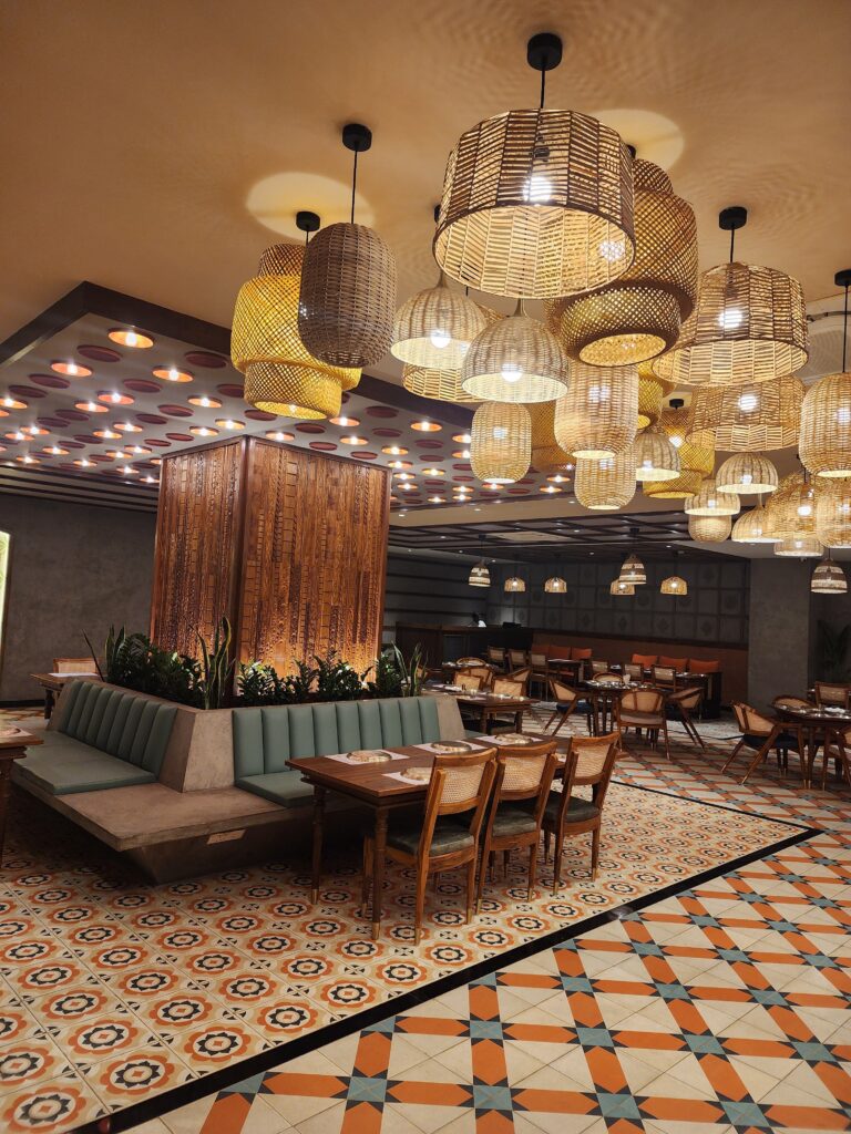 Stylish restaurant furniture by Mavensoft in a Hyderabad dining space, with cane-back chairs and wood table on patterned tile flooring.